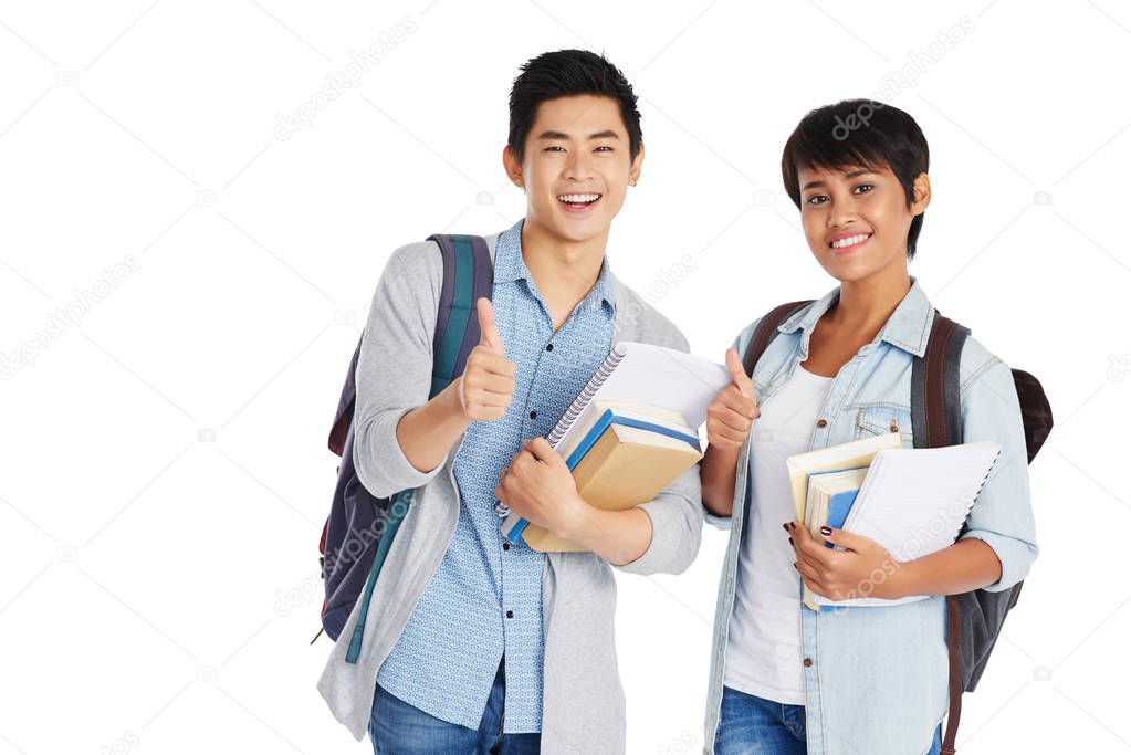 Group portrait of joyful university students showing thumbs up while posing for photography against white background