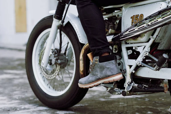 cropped shot of male foot pressing gas pedal on vintage motorcycle