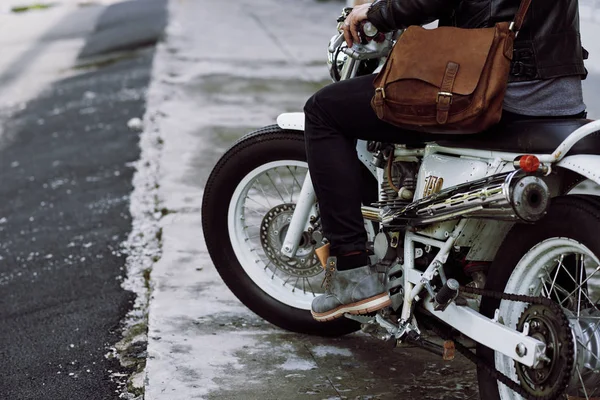partial view of biker sitting on vintage motorcycle and pressing gas pedal