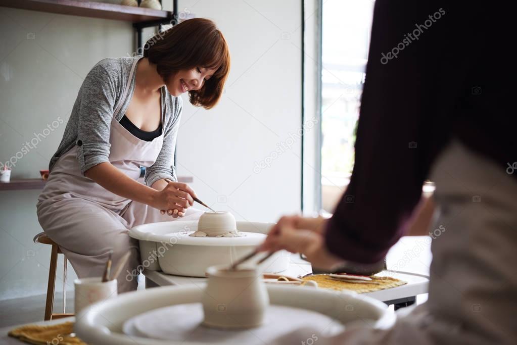 Young Vietnamese woman enjoying making pot on pottery wheel