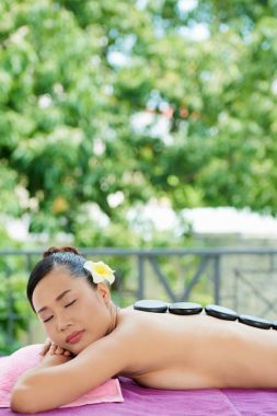 Güzel Vietnamca kadının sırtında bazalt taşlarla yalan