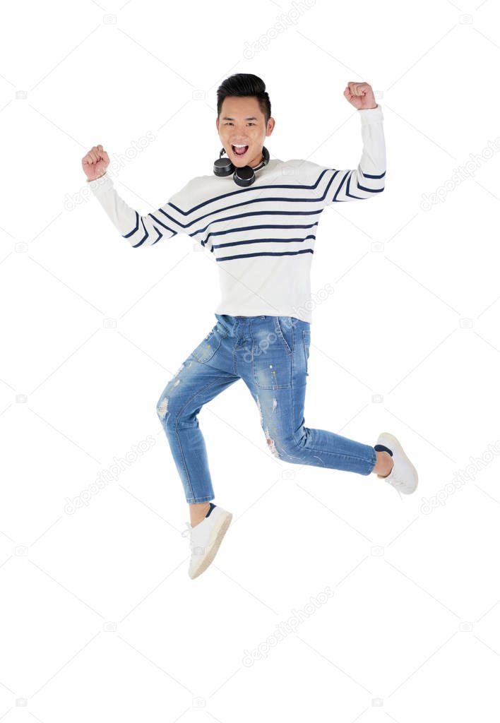 Jumping happy Vietnamese man in casual clothes jumping in studio
