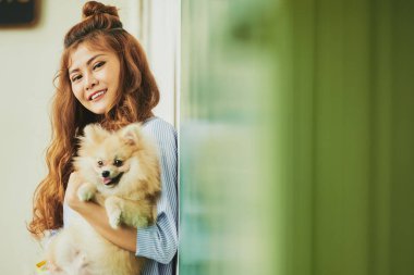 Güzel kız duvara onun elinde Pomeranian spitz ile ayakta