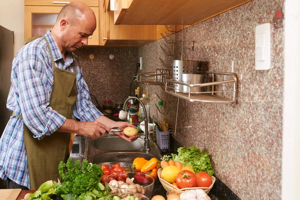 Hombre Delantal Pelando Papa Sobre Fregadero Cocina —  Fotos de Stock