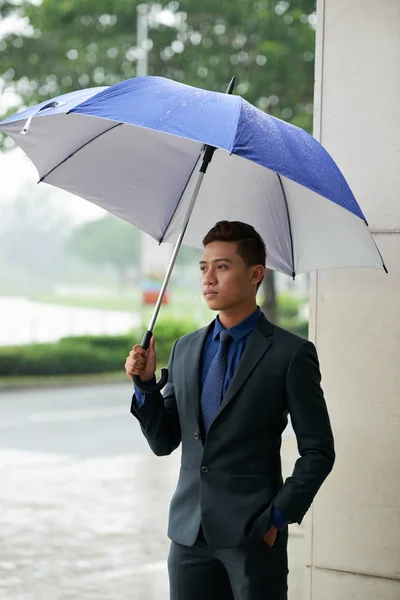 英俊的亚裔男子的肖像站在户外拿着雨伞在雨中 等待着某人 — 图库照片