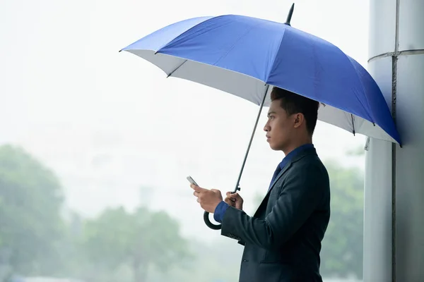 Портрет Современного Азиатского Бизнесмена Стоящего Дождливой Улице Зонтиком Смартфоном — стоковое фото