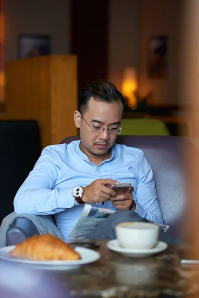 アジア系のビジネスマンが彼のスマート フォンに電子メールをチェックします — ストック写真