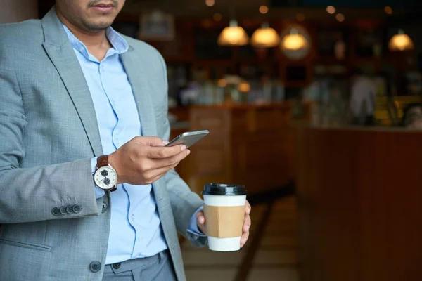 テイクアウトのコーヒーを飲みながら 携帯電話をチェックの実業家の画像をトリミング — ストック写真