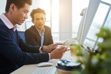 Vietnamca iş erkek masada cep telefonu ve bilgisayar kullanma