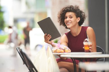 Kokteyl ve dijital tablet yenileme ile neşeli kıvırcık kadın