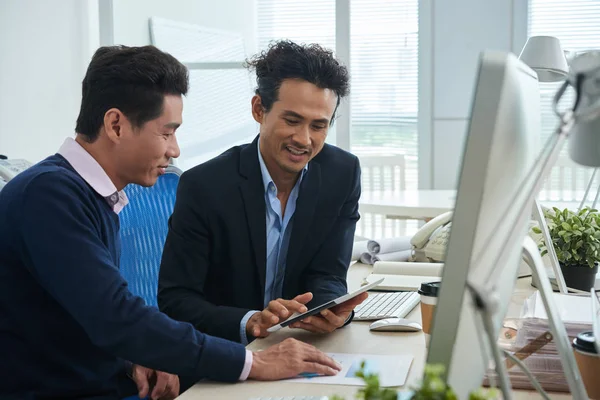 Tablet bilgisayarda veri tartışırken gülümseyen olgun arkadaşları