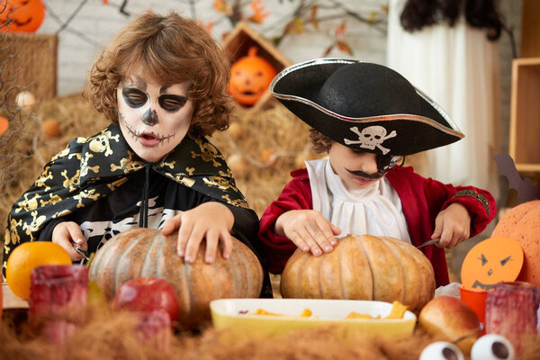 Children in Halloween costumes making decorations for party