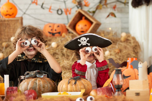 Brothers dressed for Halloween holding plastic eyeballs to make funny faces