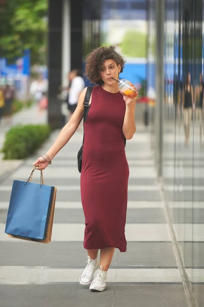 非常にのんきな女性野外を歩いていると ショッピングの後カクテルを飲む — ストック写真