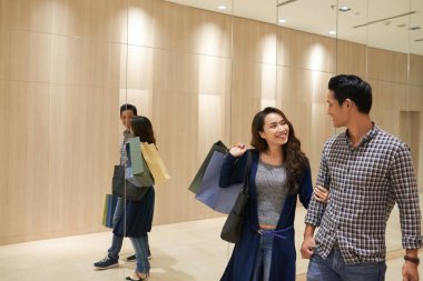 Alışveriş alışveriş merkezinde yürüyen torbaları ile neşeli genç Çift