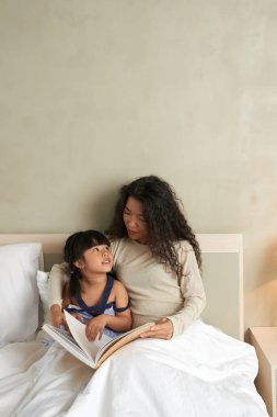 Genç Vietnamlı kadın kızı yatakta için okuma
