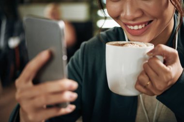Yakın çekim yansıma latte içmek kadın ve ve smartphone ekran üzerinde seyir