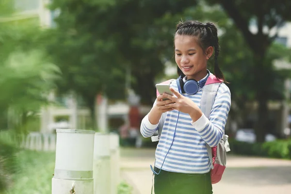 スマート フォンでアプリケーションを使用して笑みを浮かべてアジア女子高生 — ストック写真