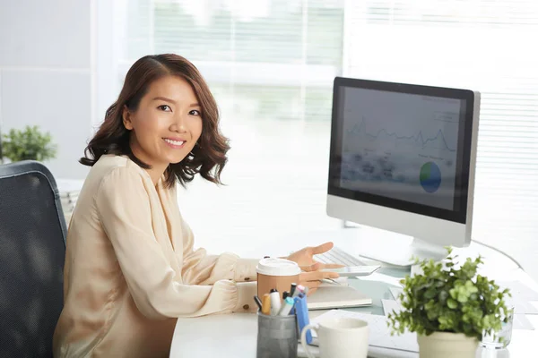 若いアジアの実業家ながら彼女の手でデジタル タブレットとコンピューターの机に座ってカメラで笑顔の肖像画 — ストック写真