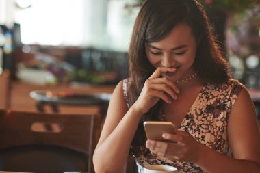 Onun smartphone içinde mesajı okurken gülümseyen güzel kadın