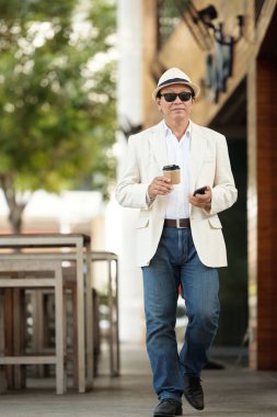 Kahve içme ve sokakta yürürken olgun adam