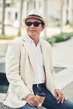 Olgun Asyalı adam açık havada oturup eve servis kahve ile portresi