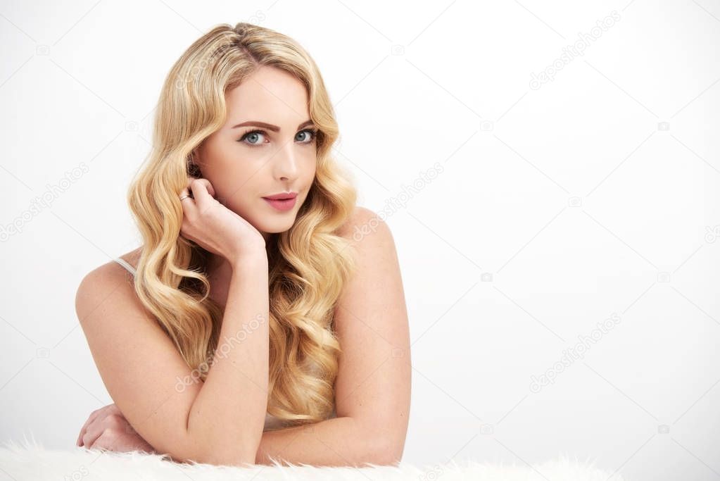 Portrait of gorgeous blonde woman with wavy hair posing against white background
