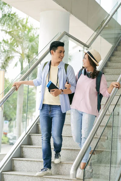 Cheerful young Asian couple walking down stairs in airport