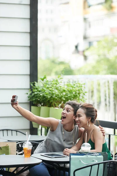 Happy female friends taking selfie in outdoor cafe