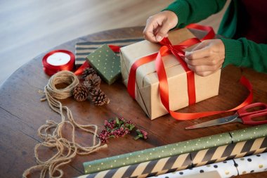 Yakın çekim yansıma Noel hediyesi süslemek için kadının bir yay kırmızı kurdele bağlama