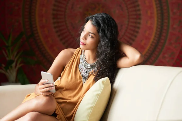 Ziemlich Nachdenkliche Junge Frau Mit Smartphone Auf Dem Sofa Liegend — Stockfoto