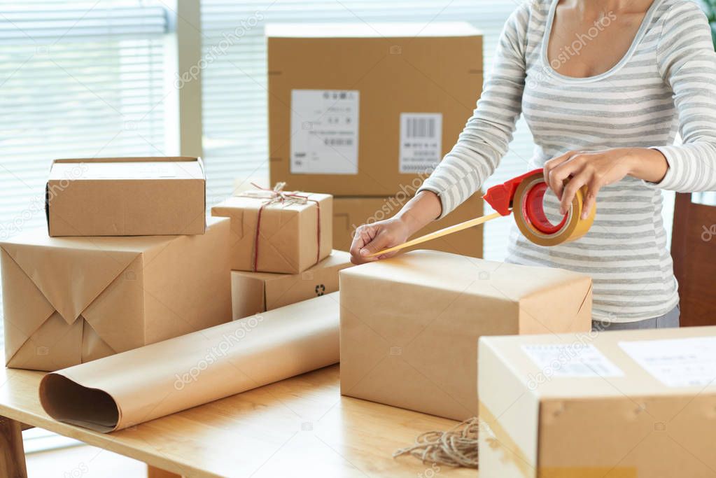 Cropped image of woman wrapping boxes to send via mail