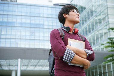 Üniversite binası önünde kitap duran yığını ile hevesli öğrenci