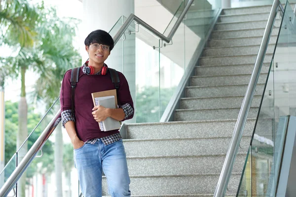 Asian high school student with textbooks standing at staircase