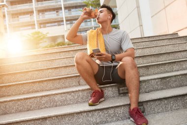 Genç jogger kulaklık açık eğitimden sonra taze su içme