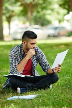 Parkta oturan ve onun ilk iş plan çalışan dalgın genç adam