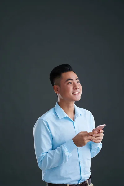 Портрет Жизнерадостного Азиатского Бизнесмена Смартфоном Смотрящего Вверх Изолированного Сером — стоковое фото