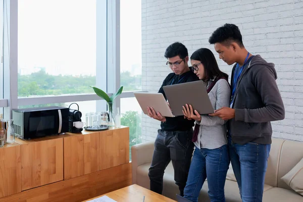 Grupo Desarrolladores Asiáticos Sosteniendo Computadoras Portátiles Oficina Mirando Pantallas Monitor —  Fotos de Stock