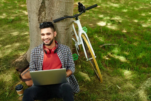 Skrattar Unga Indiska Man Sitter Trädet Med Dator Och Cykel — Stockfoto