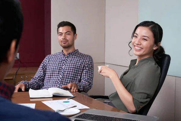 Laughing young business woman at meeting of financial managers