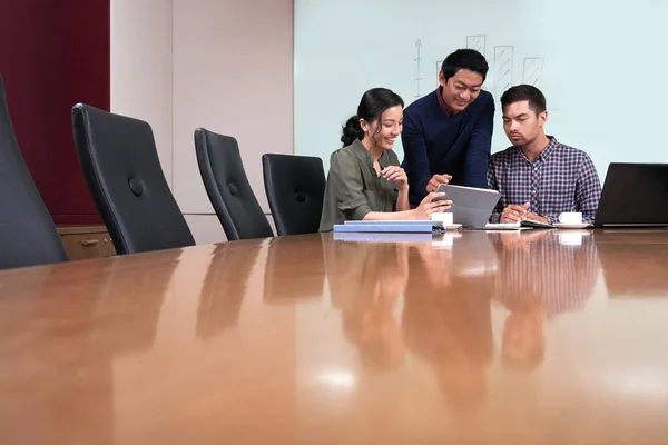 Cheerful business team discussing information on tablet computer