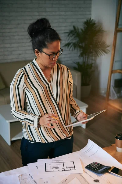 Professionele Vrouwelijke Architect Vergelijken Informatie Tablet Met Blauwdrukken — Stockfoto