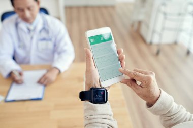 check-up sırasında nabız kontrol için etkinlik izleyicisi ve smartphone kullanarak erkek eller