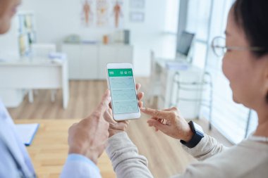 Doktor ve hasta smartphone kullanarak görünümünü omuz üzerinde 