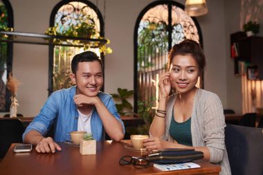 Portrait of young Asian man flirting with beautiful woman in cafe clipart