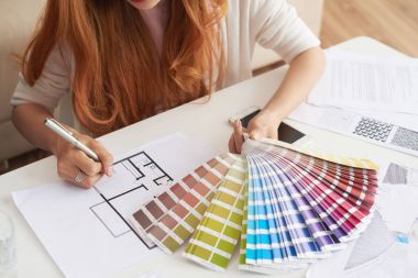 Closeup portrait of young woman working with floor plans and color swatches choosing interior design for new house