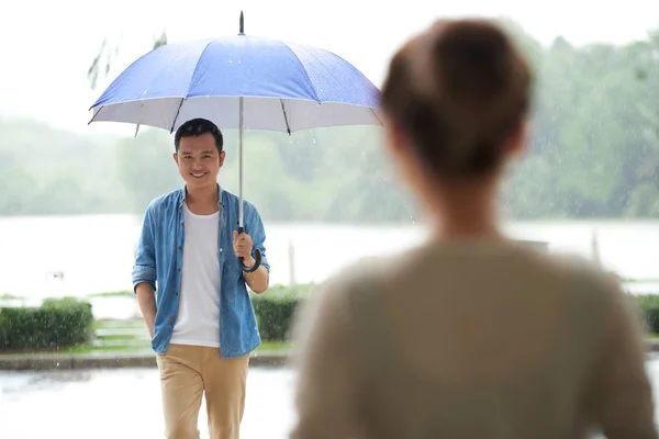 傘の下で雨の中で立っていると笑っている彼のガール フレンドを満たす若い男性の肖像画 — ストック写真