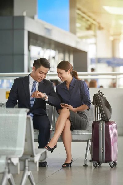 アジアの男性と女性の空港出発ゾーンで待っている間の時間をチェック — ストック写真