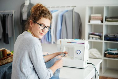 Dikiş geri dönüş ve kameraya bakarak, oldukça gülümseyerek terzi
