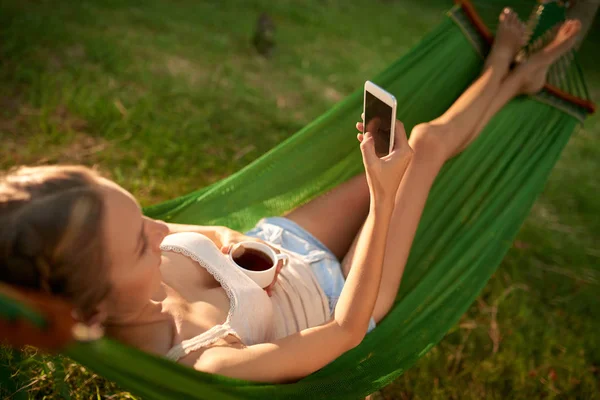 Vrouw Met Behulp Van Mobiele Telefoon Terwijl Liggend Een Hangmat — Stockfoto